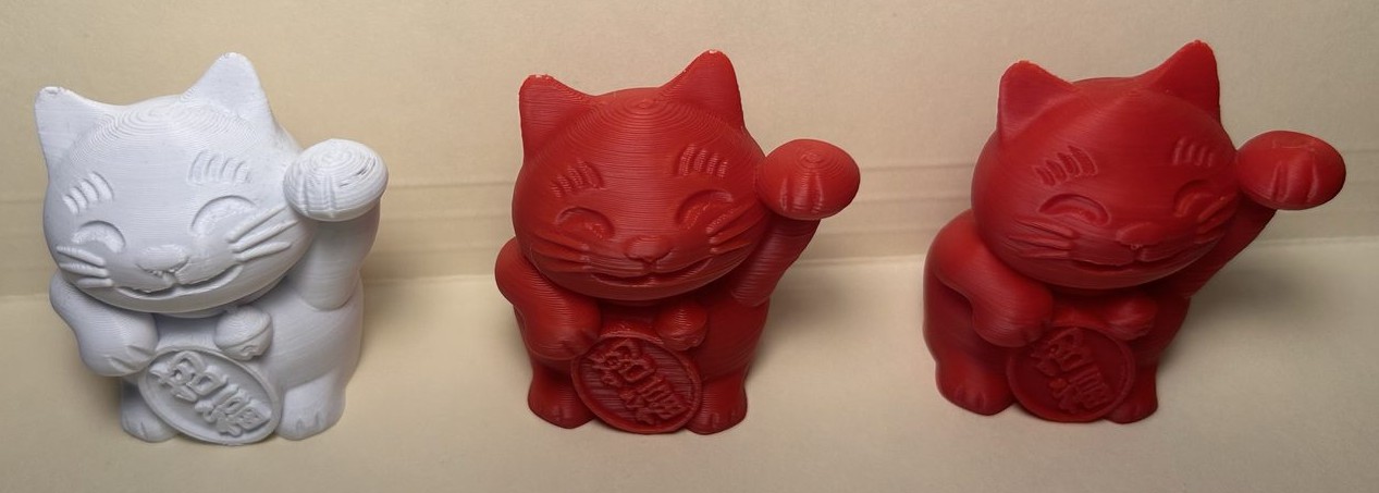 Three printed lucky cat models at a 45 degree angle: the white original from the stock setup, and two red prints from the rebuilt machine using the Speed and Quality profiles